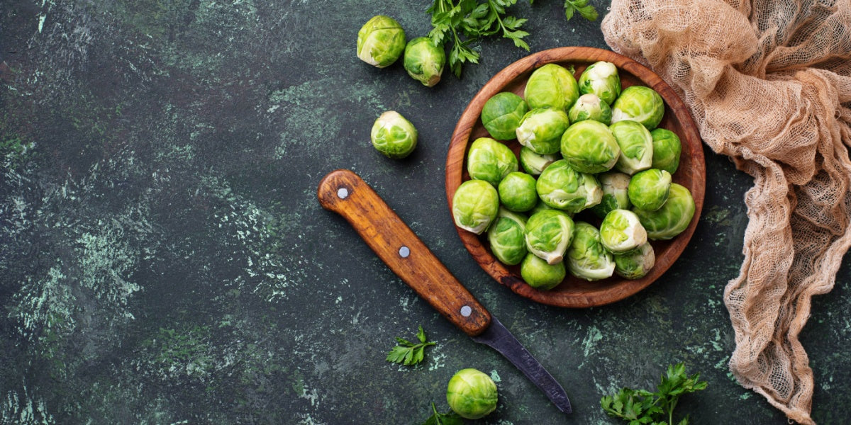brussels sprouts in a wooden bowl and a wooden knife on a table