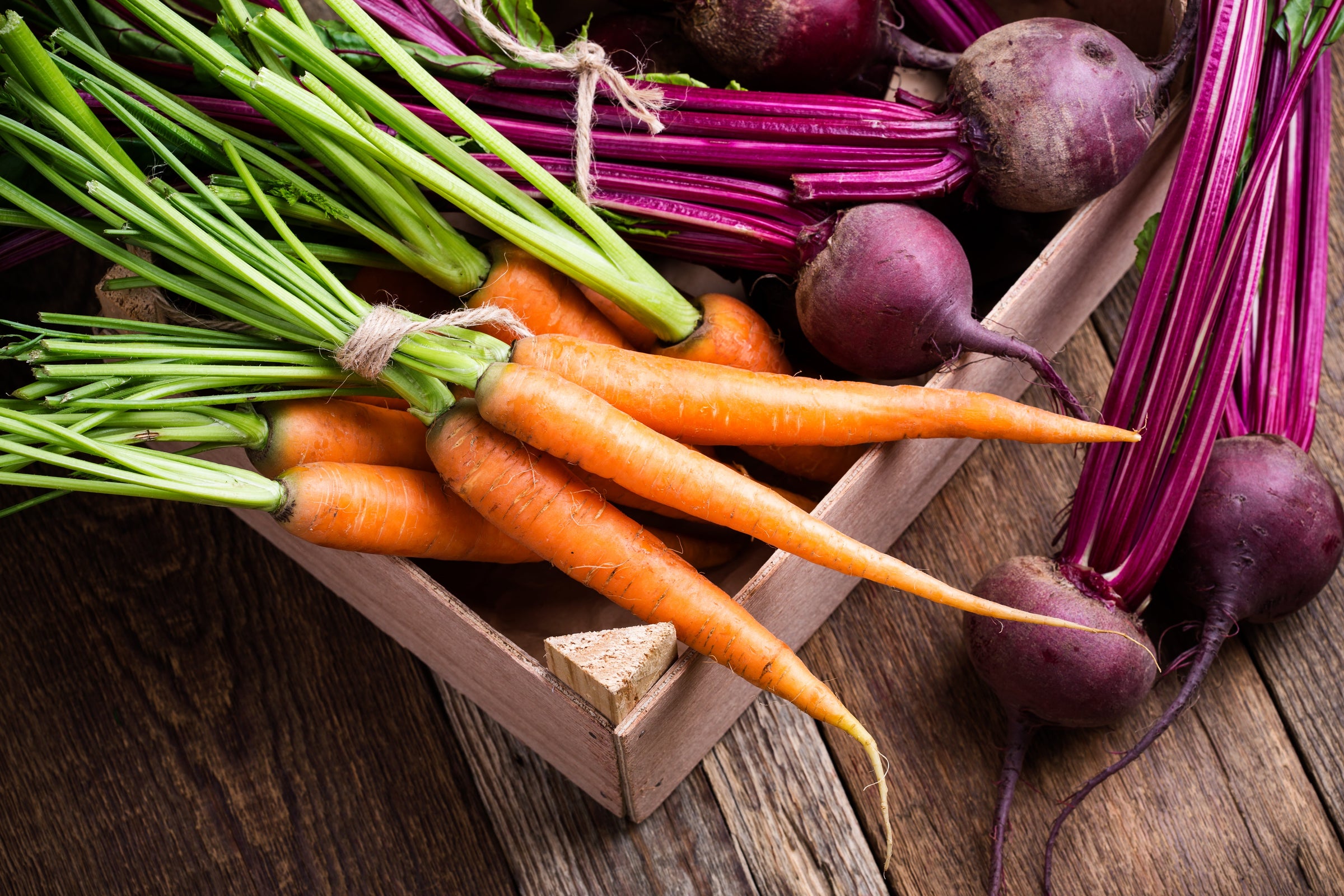 carrot and beetroot root vegetables in a wooden box crate on a wooden table